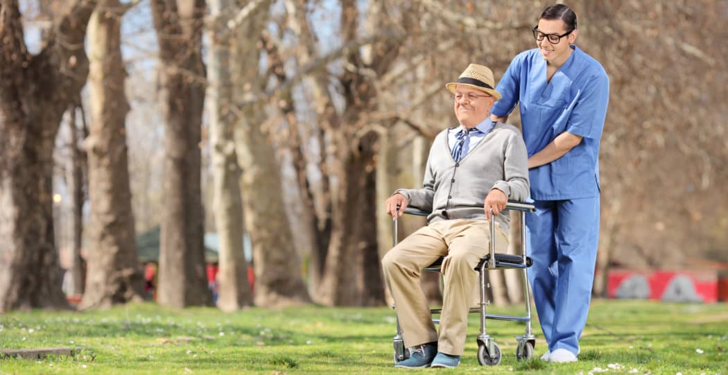 caregiver pushing and senior man on a wheelchair
