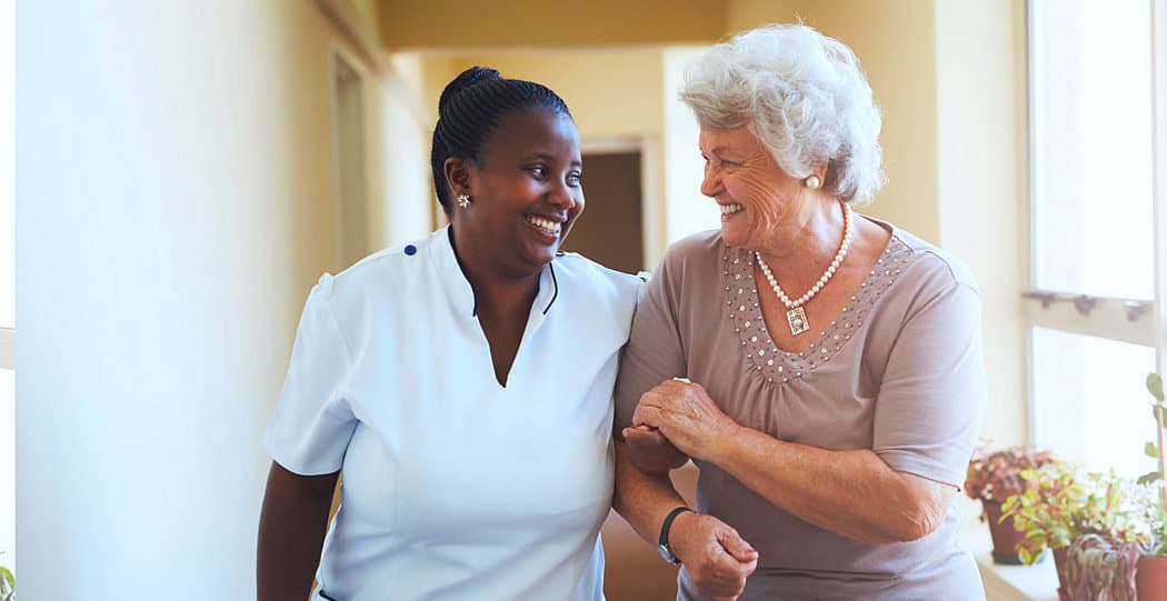 caregiver and senior woman smiling each other